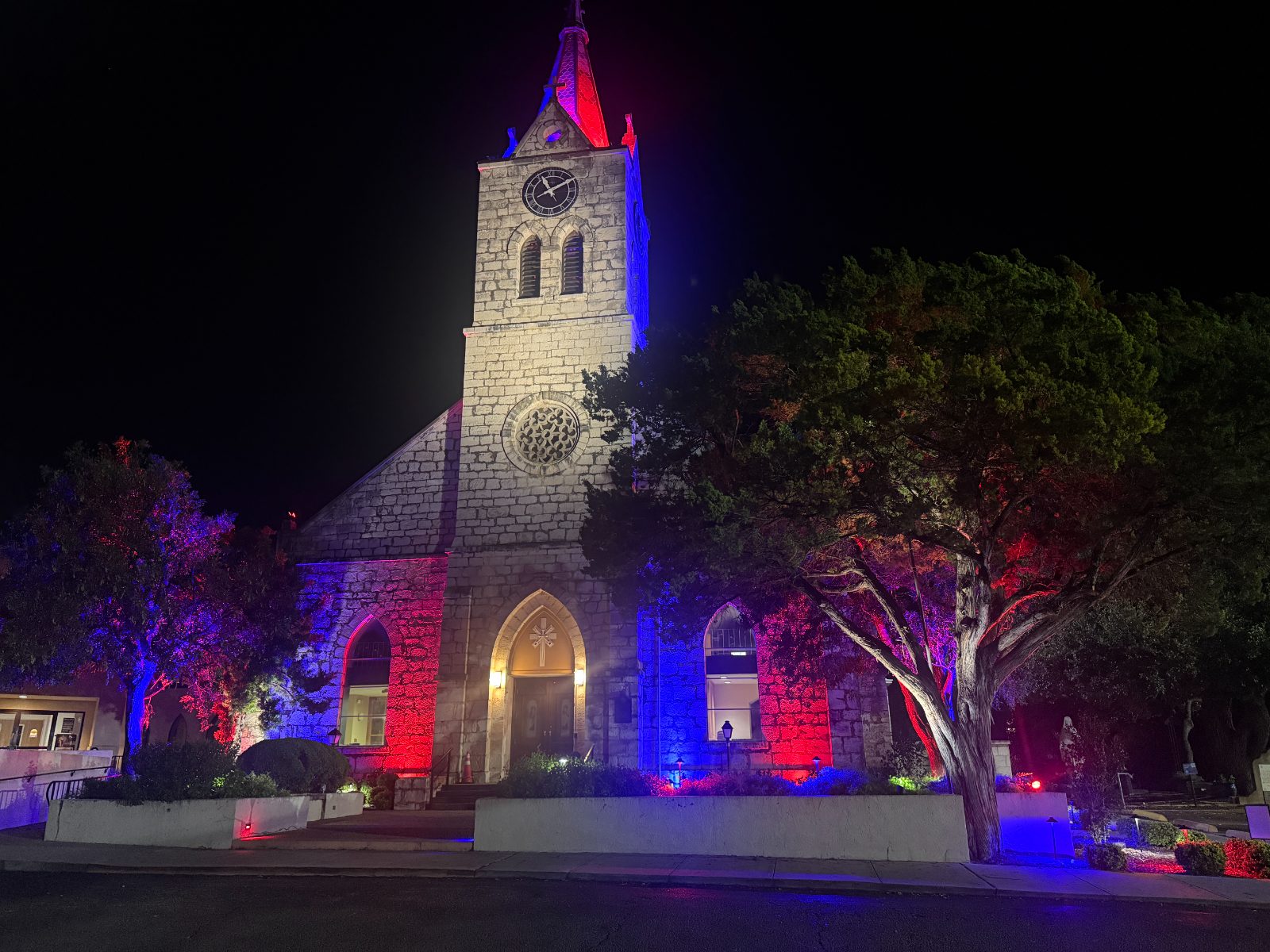 Stone church facade lit in red, white and blue.
