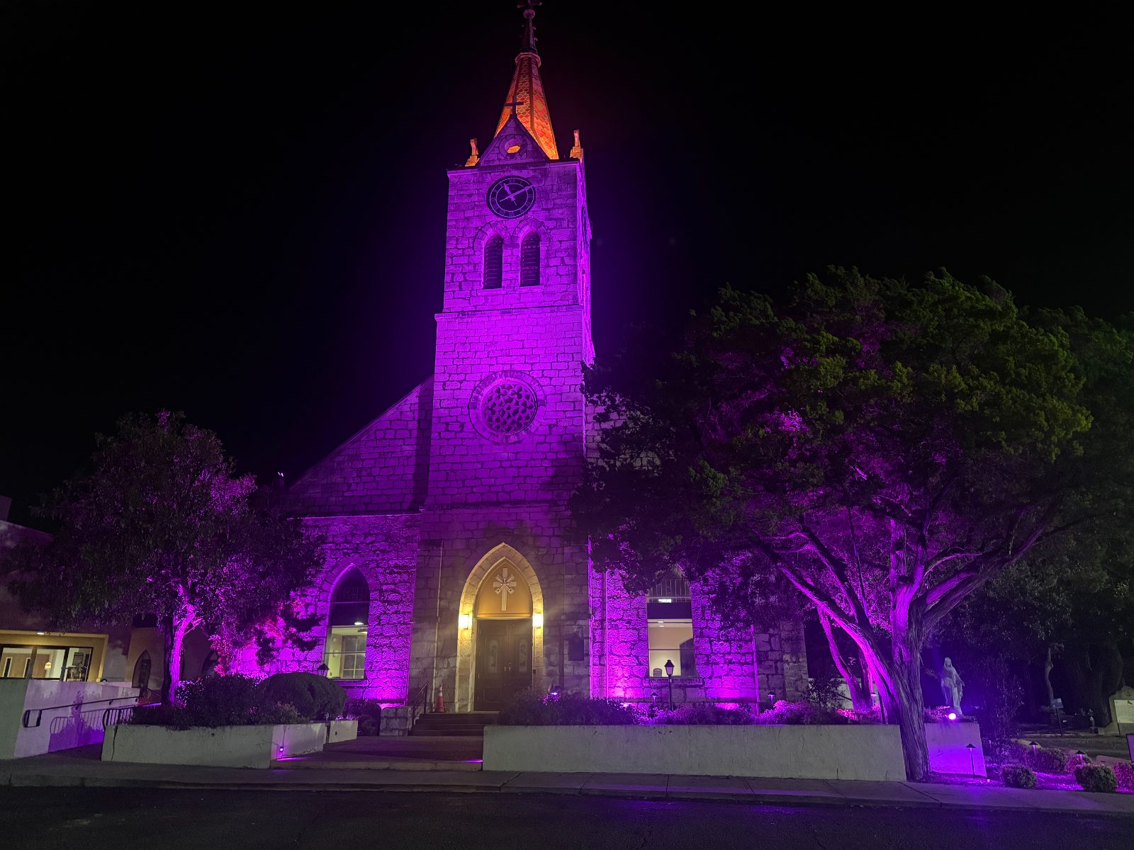 Stone church facade lit in liturgical purple.