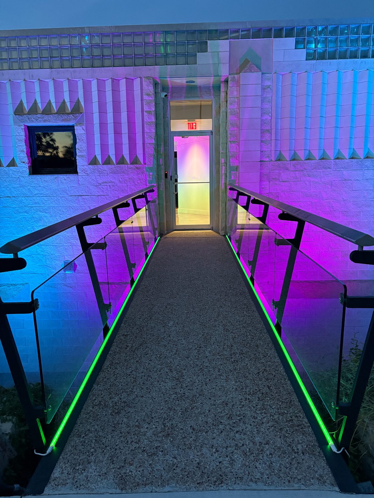 Commercial entrance ramp traced with green LED accents and purple facade washes.